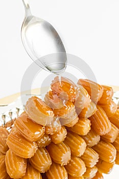 Traditional Turkish Fried Dough Dessert,Tulumba,puring syrup with spoon on the shiny metal tray.