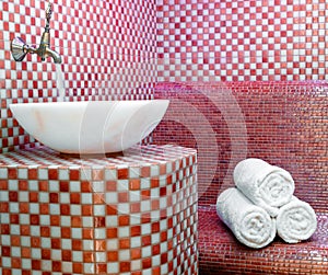 Traditional Turkish hamam with stone walls, sink and stack of towels