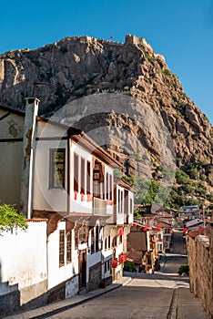 Traditional Turkish Ottoman houses in Afyonkarahisar Turkey. Afyon Castle on the rock and Mevlevihane Museum in front of it