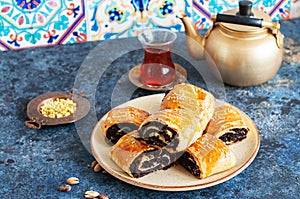 Traditional turkish pastry roll with chocolate and nuts filling in a plate and tea on a blue bakground