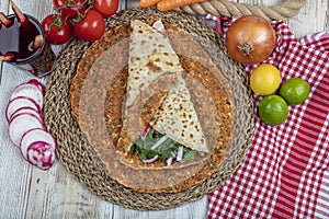 Traditional Turkish pizza, called Lahmacun, being prepared with meat, onion and parsley, displayed on a wooden table at a a street