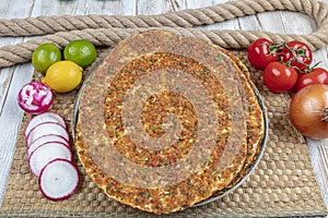 Traditional Turkish pizza, called Lahmacun, being prepared with meat, onion and parsley, displayed on a wooden table at a a street