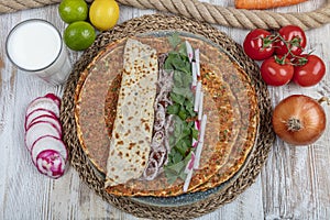 Traditional Turkish pizza, called Lahmacun, being prepared with meat, onion and parsley, displayed on a wooden table at a a street