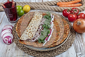 Traditional Turkish pizza, called Lahmacun, being prepared with meat, onion and parsley, displayed on a wooden table at a a street