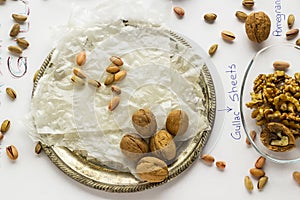 Traditional Turkish Ramadan Dessert Gullac sheets on metal tray with walnuts and pistachio nuts.