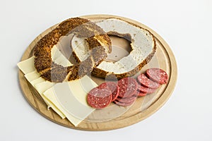 Traditional Turkish sesame bagel cut in half on wooden plate with sausage