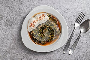 Traditional Turkish spinach meal with rice and minced meat with yogurt on a white porcelain plate