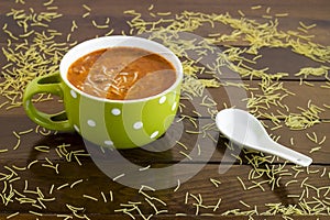 Traditional Turkish vermicelli soup in green mug on wooden table