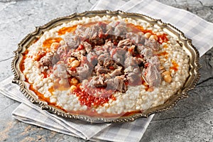 Traditional Turkish Wheat Stew With Mutton Meat, with butter and red pepper sauce closeup on the plate. Horizontal