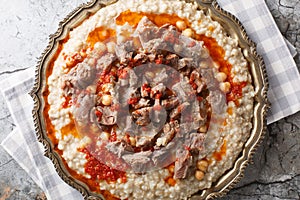 Traditional Turkish Wheat Stew With Mutton Meat, with butter and red pepper sauce closeup on the plate. Horizontal top view