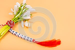 Traditional twisted red and white thread around snowdrops bouquet, romanian tradition of 1st of march martisor