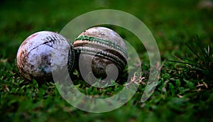 Traditional two white used cricket balls on a ground