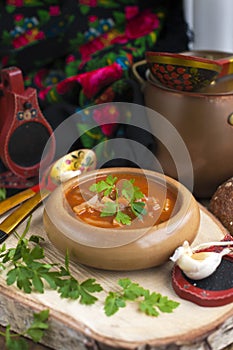 Traditional Ukrainian beet soup borscht in wooden bowl with garlic buns pampushka and dry cured pork belly on rustic wooden table