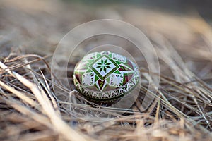 Traditional Ukrainian Easter egg in green-brown colors on a background of hay