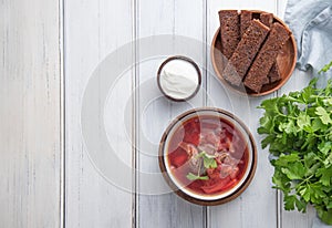Traditional Ukrainian Russian borsch beetroot soup with meat in a black bowl on a  wooden background with slices of fried bread