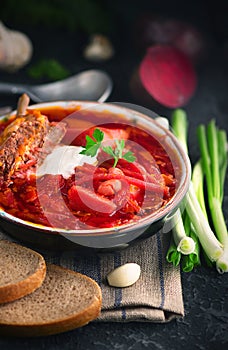 Traditional Ukrainian russian borscht. Plate of red beet root soup borsch on black rustic table. Beetroot soup