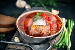 Traditional Ukrainian russian borscht. Plate of red beet root soup borsch on black rustic table. Beetroot soup