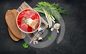 Traditional Ukrainian russian borscht. Plate of red beet root soup borsch on black rustic table. Beetroot soup