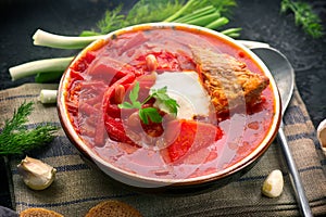 Traditional Ukrainian russian borscht. Plate of red beet root soup borsch on black rustic table. Beetroot soup