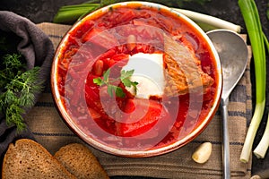 Traditional Ukrainian russian borscht. Plate of red beet root soup borsch on black rustic table. Traditional Ukrainian cuisine