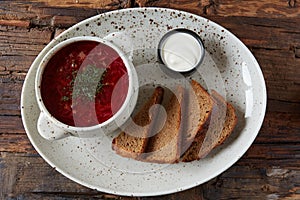 Traditional Ukrainian Russian borscht with white beans on the bowl. Plate of red beet root soup borsch on black rustick