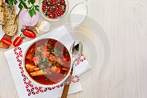 Traditional Ukranian soup borsch on a white napkin embroidered in red, copy space, top view.