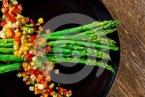 A traditional vegetarian salad from white asparagus, cocktail tomatoes and rugula with green on a rustic wooden table