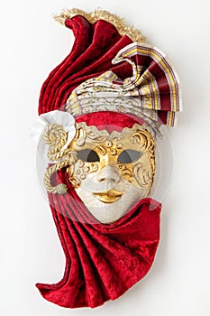 Traditional Venetian mask with red and gold decor isolated on white background.