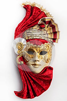 Traditional Venetian mask with red and gold decor isolated on white background.