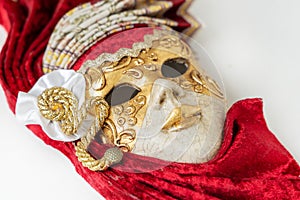Traditional Venetian mask with red and gold decor isolated on white background.