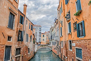 Traditional Venice gondola parked in the canal, with no people inside and the typical Venice ancient building in the background.