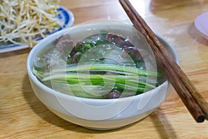 Traditional Vietnamese beef noodle soup with green onions, medium rare beefs, rice noodles eating with bean sprouts and lime. Pho