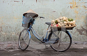 Traditional Vietnamese bicycle load with vegetables and conical hat rested on the handlebar. photo