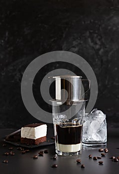 Traditional vietnamese coffee maker placed on the top of glass, glass with ice and souffle dessert