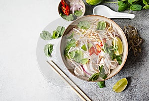 Traditional Vietnamese soup- pho ga in bowl with chicken and rice noodles, mint and cilantro, red onion, chili, bean sprouts and