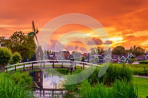 Traditional village with dutch windmills and river at sunset, Holland, Netherlands.