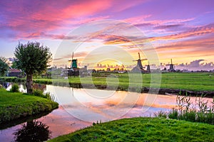Traditional village with dutch windmills and river at sunset, Holland, Netherlands.