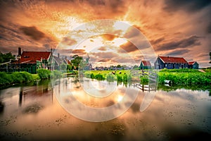 Traditional village with dutch windmills and river at sunset, Holland, Netherlands.