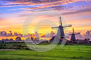 Traditional village with dutch windmills and river at sunset, Holland, Netherlands.