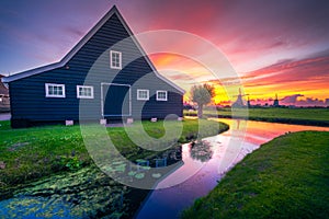 Traditional village with dutch windmills and river at sunset, Holland, Netherlands.