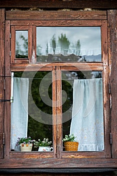 Traditional vintage old brown wooden frame window with curtains and flowers