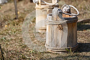 Traditional vintage russian wooden water bucket stands on the grass in summer, selective focus.
