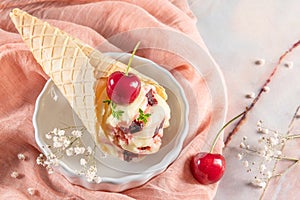 Traditional waffle cones with ice cream and cherry fruits on marble stone surface