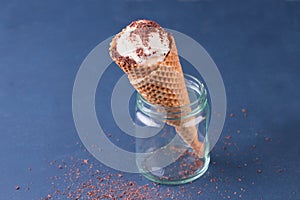 Traditional waffle cones for ice cream in glass jar on blue table. Cones filled with ice cream