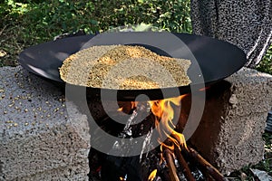 Traditional way to roast wheat on fire of a stone stove