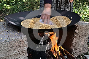 Traditional way to roast wheat on fire of a stone stove