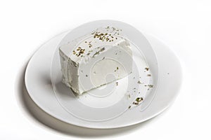 Traditional white Greek feta and oregano cheese on a white plate on a white background