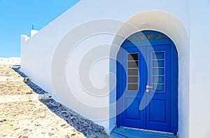 Traditional white Greek house facade with blue door Santorini, Greece