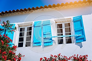 Traditional white greek white with blue window shutter in Mediterraneanstyle and rosa flowers. Fiskardo, Kefalonia