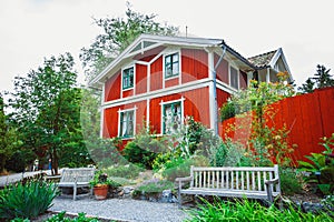 A traditional white and red painted wooden house building in Skansen open-air museum at sunny summer day. Stockholm,